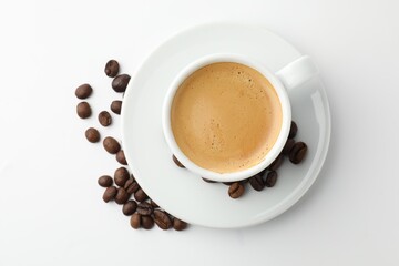 Cup of aromatic coffee and roasted beans on white background, flat lay