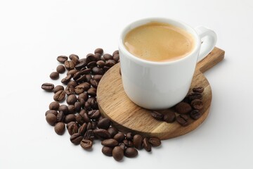 Cup of aromatic coffee and roasted beans on white background, closeup