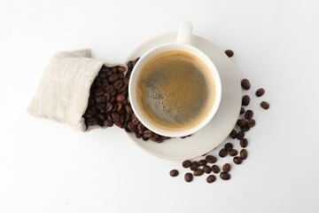 Cup of aromatic coffee and roasted beans on white background, flat lay