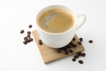 Cup of aromatic coffee and roasted beans on white background, closeup