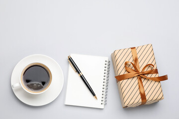 Beautiful gift box, notebook, pen and cup of coffee on white background, flat lay. Space for text