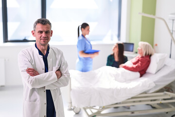 Fototapeta premium Doctor stands confidently in hospital room while nurses attend to patients in need of care
