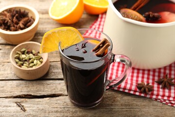 Mug with tasty mulled wine and ingredients on wooden table, closeup