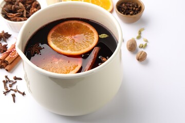 Tasty mulled wine in pot and ingredients on white table, closeup. Space for text