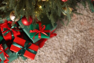 Many gift boxes under Christmas tree on floor indoors, flat lay. Space for text