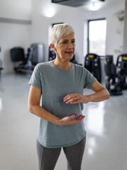 Older adult practices chi gong exercises in gym