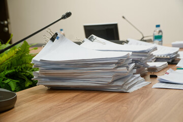 Huge stacks of sorted paper documents with binder clips on a conference table with a microphone. Concept of bureaucracy and budget reporting. Photo