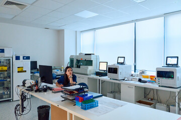 Laboratory setting featuring a female scientist engaged in research work amid advanced equipment and a clean workspace during daylight hours