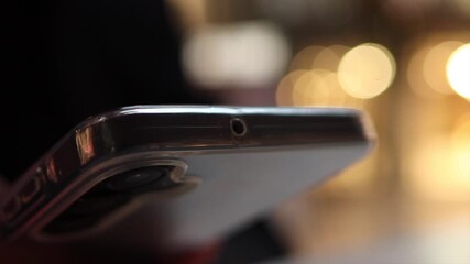 Hand holding smartphone to tap for contactless payment at a pos terminal, modern mobile nfc transaction in a retail checkout with soft bokeh lights in the background - Powered by Adobe