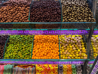 Rows of glossy chocolate style nuts displayed under decorative lighting in a market stall in bazaar Istanbul. Sensory richness, indulgent mood, visual density, and confectionery attraction through