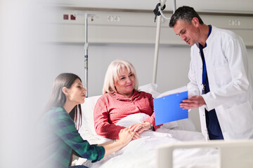 Obraz premium Doctor discusses treatment plan with patient and family in hospital room setting during daytime