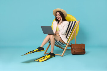 Businesswoman with laptop and flippers in deck chair on light blue background © New Africa