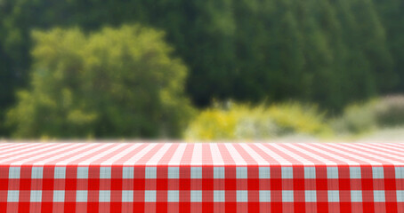 Empty red and white checkered tablecloth for picnic over green background 
