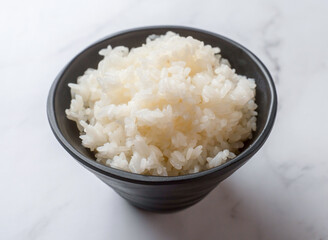 Steaming bowl of white rice on marble surface