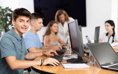 Fototapeta premium Engrossed in his work, student sits near computer, fully immersed in his studies.