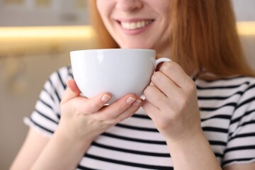 Woman with cup of aromatic coffee indoors, closeup