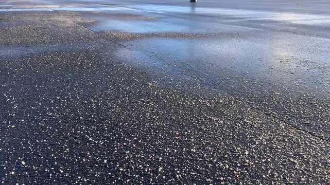 Deicing chemicals on the street in winter. Salt grains on icy sidewalk, asphalt with rock salt in cold season. Slippery road sprinkled with technical salt and calcium. Prevent slipping concept