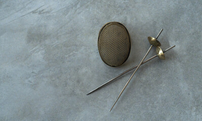 Fencing helmet and swords on the table.Background for fencing.Miniature brass sword.