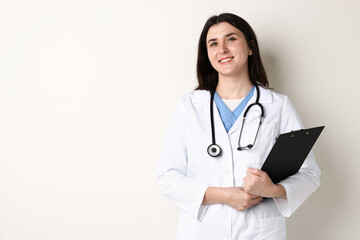 Fototapeta premium Doctor in medical uniform with clipboard and stethoscope on white background, space for text
