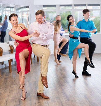 Dynamic pair engaging in Latino dance in dance studio. Pairs training ballroom dance in hall
