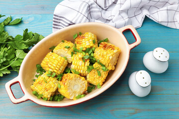 Pieces of grilled corn cobs with green onions on blue wooden table, flat lay