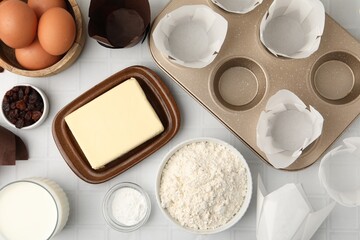 Ingredients for making muffins and cupcake tray on white tiled table, flat lay