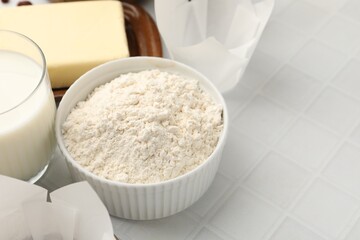 Ingredients for making muffins on white tiled table, closeup. Space for text