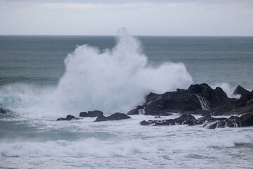 Powerful ocean wave crashing against dark rocks