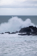 Ocean waves crashing on dark rocks with foam