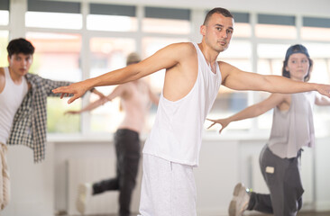 Group of energetic hip-hop dancers focused on training while gathered together in spacious dance hall