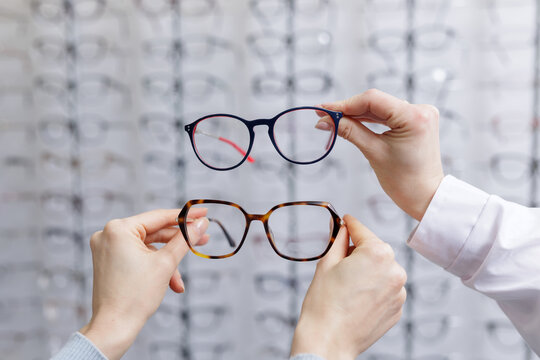 Hands comparing two eyeglass frames in optical store choosing eyewear for vision correction