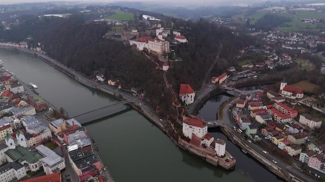 Drohnenvideo der Veste Oberhaus auf dem St. Georgsberg ueber der Dreifluessestadt Passau. Im Bild: Donau, Inn, Ilz, Veste Niederhaus und die Wallfahrtskirche St. Salvator im winterlichen Grau