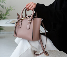 Small taupe leather handbag with gold details, structured design, styled with a black blazer and white trousers