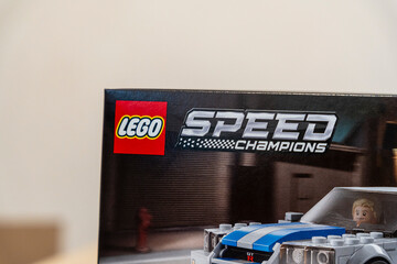 Naklejka premium Warsaw, Poland - Dec 16, 2025: A close-up of a LEGO Speed Champions box featuring a racing car and a mini figure, showcasing vibrant colors and a dynamic design, ideal for play or display.
