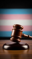 Gavel on judge's table with transgender pride flag in background reflecting equality and justice