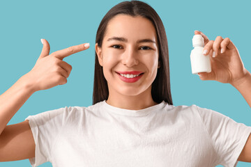 Young woman with eye drops on blue background, closeup