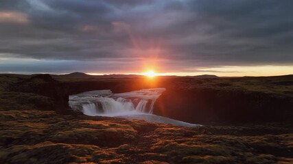 Nature's Grand Finale The Setting Sun's Fiery Hues Reflect on a Cascading Waterfall in an Untouched Wilderness, Evoking Tranquility