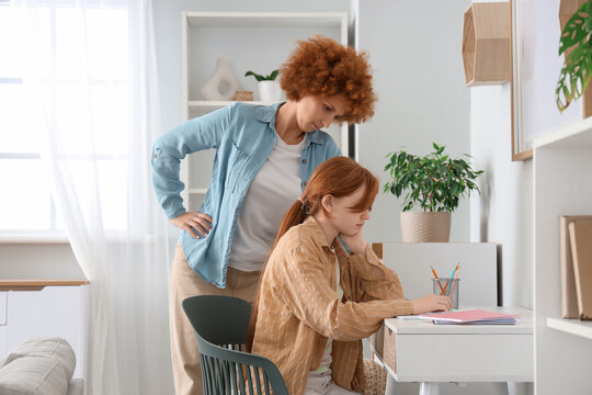 Redhead mother squabbling with her teenage daughter over lessons at home