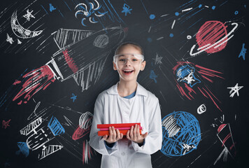Studying science. Child holding books near green board with chalk drawings