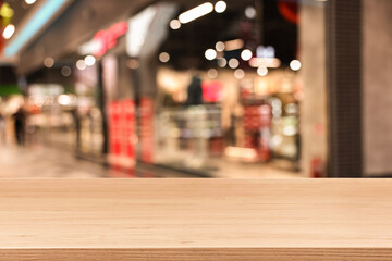 Empty wooden table against blurred view of shopping mall. Space for design