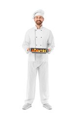 Male chef with tasty vegetables in baking dish on white background