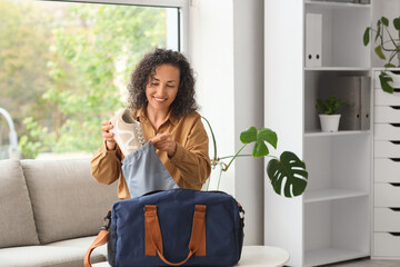 Mature businesswoman with sports bag sitting on sofa in office
