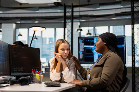 Young employee confiding personal struggles to her friend at work during office break, receiving mutual reassurance. Wise african american woman supporting coworker facing challenges