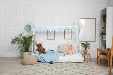 Interior of children's room with blank frames, bed and shelf unit