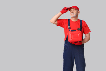 Mature male mechanic with canister on white background