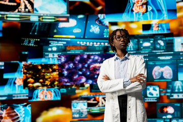 Woman in white lab coat standing in front of digital health dashboards backdrop, analyzing human anatomy. African american scientist reviewing medical scans visualizations projected on videowall