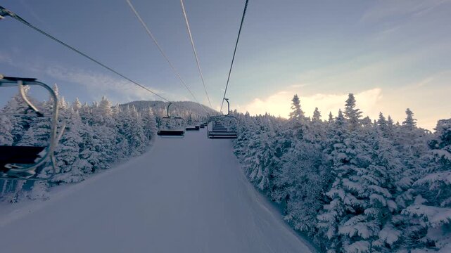 Ski chairlift at Killington Mountain, Vermont. Riding a lift in winter while snow skiing and snowboarding with white snowy trees and mountains. 4K video.