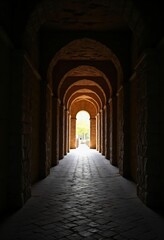Fototapeta premium A long dimly lit stone hallway with arched ceiling. Historic architecture showing perspective and the path ahead. Concept of journey.