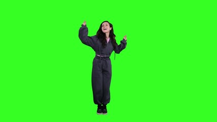 Happy young woman dancing while looking up on the chroma key