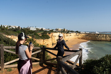 A mother and daughter enjoying the beautiful view Yellow rocks and cliffs on the sandy beach. A cove by the sea, Our Lady of the Rock, Praia Nova, Lagos. Algarve, Portugal
